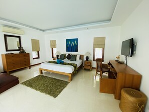 A hotel room with a bed, a desk, a chair, a dresser, a TV, and a window with a view.