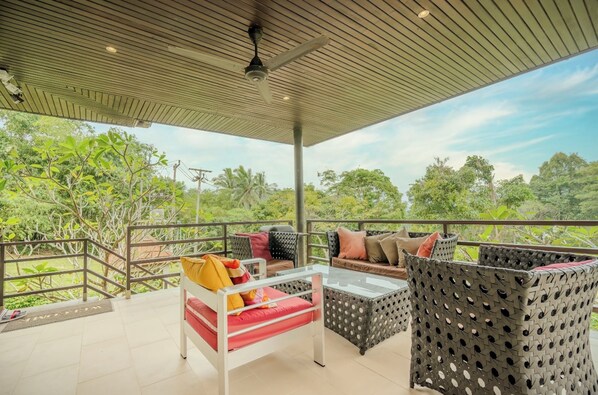 A covered outdoor seating area with wicker furniture and a glass table, overlooking a lush garden. - 2 Bedroom Villa Nature SDV004-By Samui Dream Villas (Koh Samui)