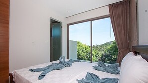 Una habitación de hotel con una cama grande, vista a zonas verdes y una puerta a la izquierda.