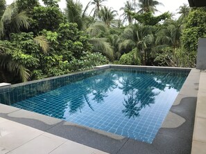 A rectangular swimming pool with blue tiles surrounded by lush greenery and palm trees. - 4 Bedroom Villa Duplex AB SDV005/006-By Samui Dream Villas (Koh Samui)