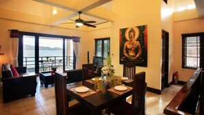 A dining area with a table set for four, a Buddha statue on the wall, and a view of the sea through large windows. - 6 Bedroom Bay & Island View Twin Villa Koh Phangan SDV233/234-By Samui Dream Villas  (Ko Pha-ngan)
