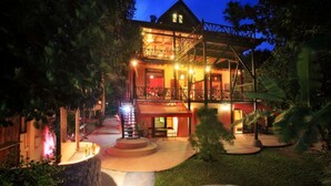 A two-story building with a balcony and outdoor seating area, surrounded by trees and a small water feature. - 10 Bedroom Sea Front Twin Villa Koh Phangan SDV232/234-By Samui Dream Villas (Ko Pha-ngan)
