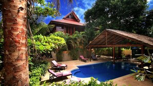 A pool area with lounge chairs, a covered seating area, and a building with a red roof. - 10 Bedroom Sea Front Twin Villa Koh Phangan SDV232/234-By Samui Dream Villas (Ko Pha-ngan)
