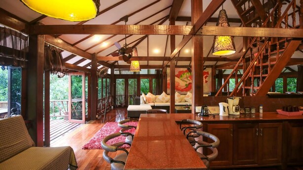 A wooden interior with a dining table, chairs, a sofa, and a staircase. - 10 Bedroom Sea Front Twin Villa Koh Phangan SDV232/234-By Samui Dream Villas (Ko Pha-ngan)