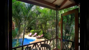 A view from a covered balcony overlooking a pool area with lounge chairs and palm trees. - 10 Bedroom Sea Front Twin Villa Koh Phangan SDV232/234-By Samui Dream Villas (Ko Pha-ngan)