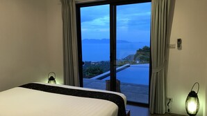 Un dormitorio con cama, vista al mar y balcón.