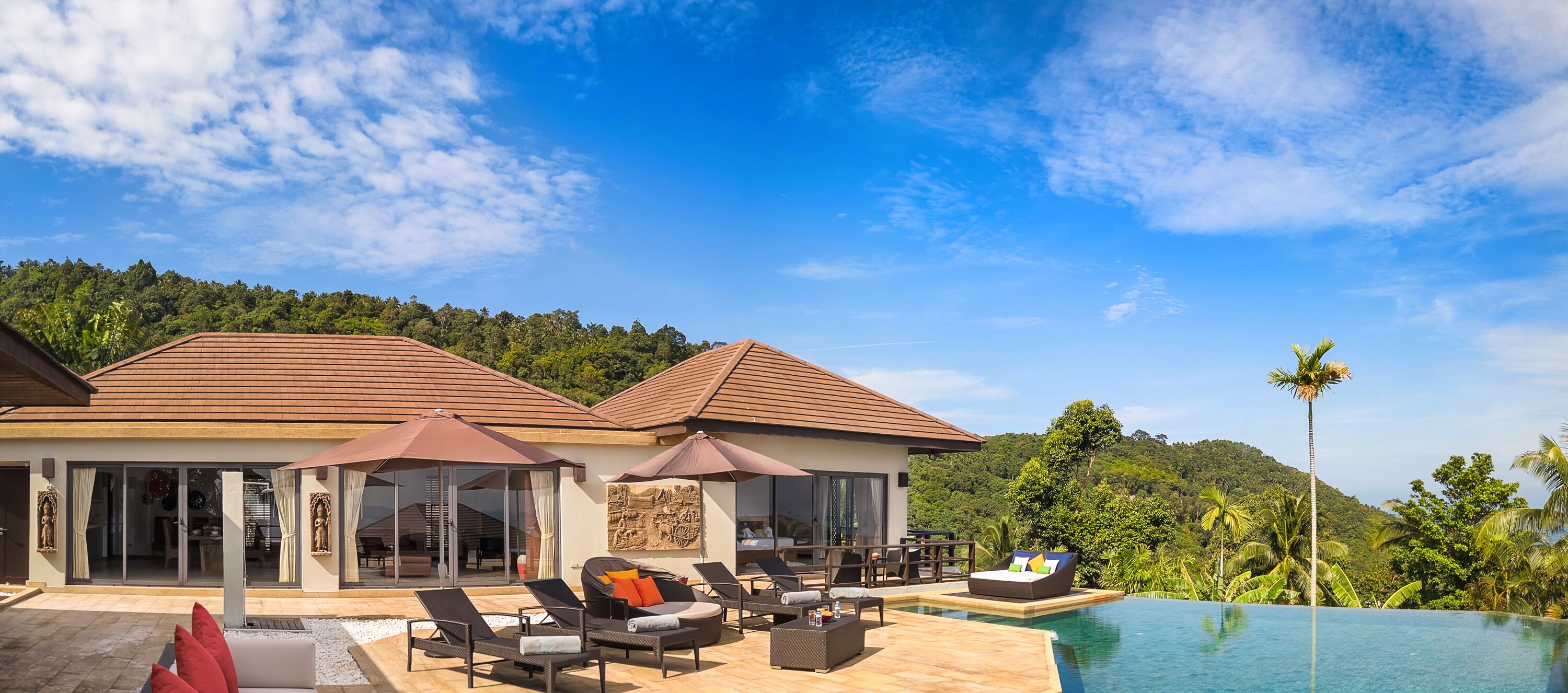 A resort with a pool, outdoor seating, and a view of the forest.