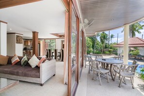 A modern living area with a sofa, dining table, and chairs. There is a large window providing a view of the outdoors. - 7 Bedroom Twin Villas TG48+TG25 on Beach Front Resort SDV282/288-By Samui Dream Villas (Koh Samui)