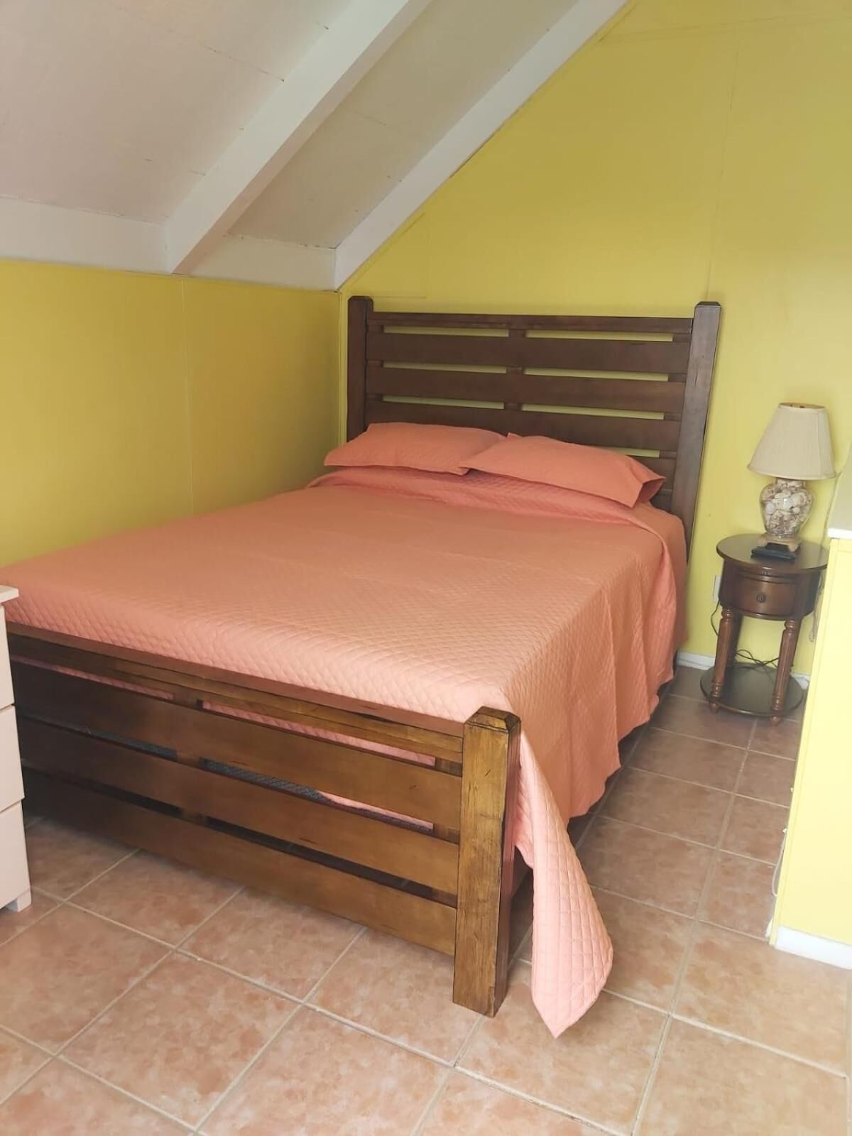 A bedroom with a wooden bed, a nightstand, and a lamp.