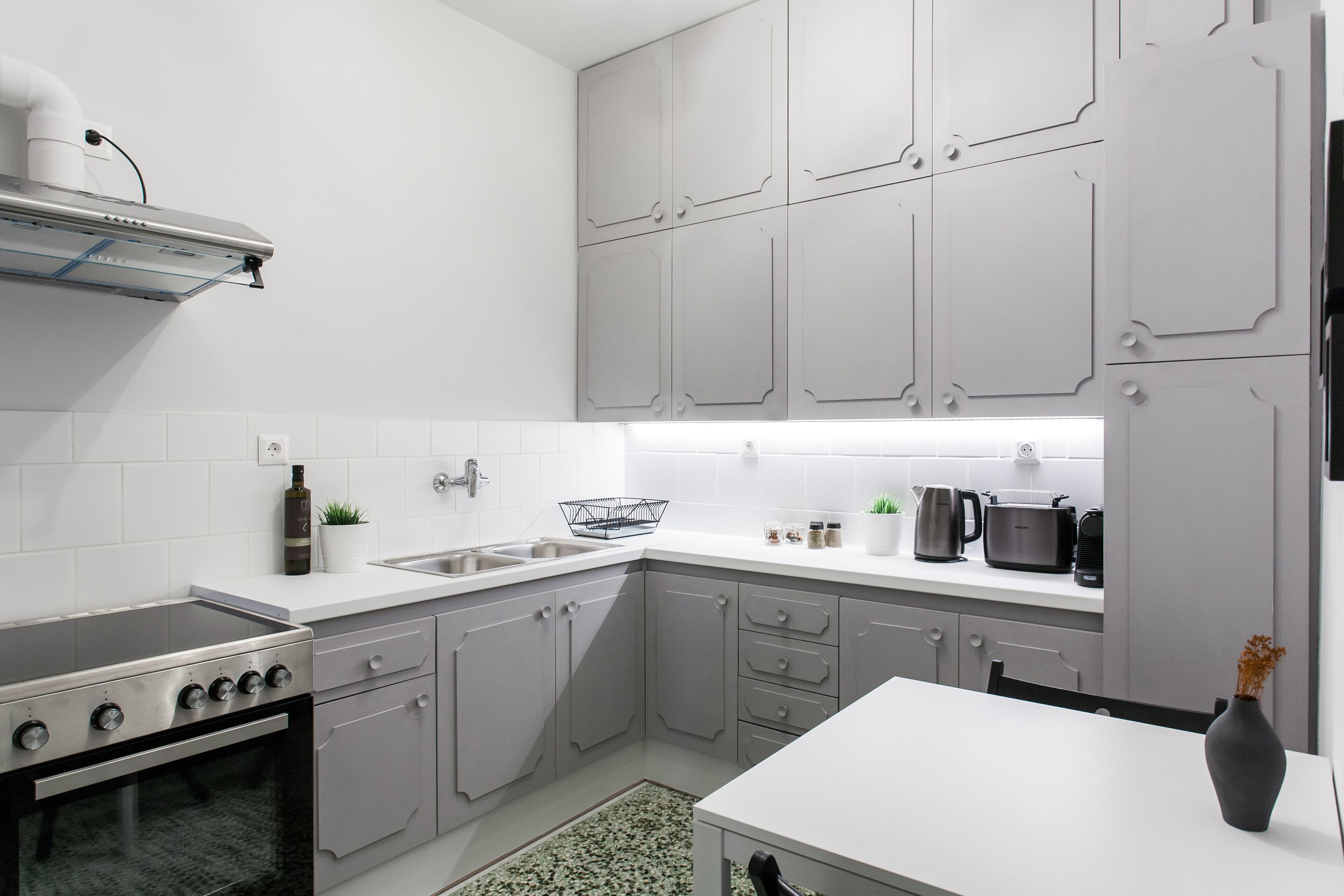 A modern kitchen with grey cabinets, a stainless steel stove, and a white countertop.