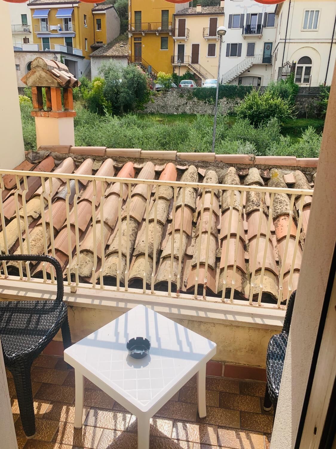 A balcony with terracotta tiles, a white table, and wicker chairs.