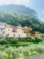Un pueblo en una ladera con edificios coloridos, un muro de piedra y abundante vegetación.