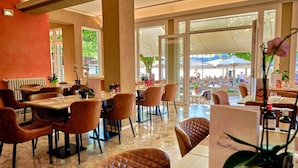Un restaurant doté d’une salle à manger, de grandes fenêtres et offrant une vue sur l’espace extérieur.