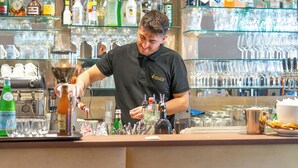 Un espace bar avec des étagères remplies de bouteilles d’alcool et de verres.