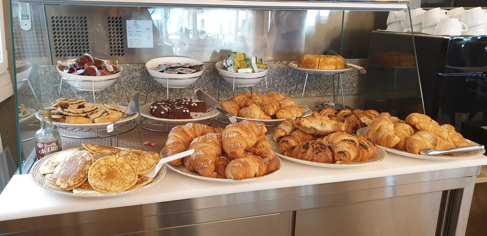 Ein Buffet mit verschiedenen Backwaren, darunter Pfannkuchen, Croissants und Gebäck.