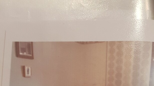 Ein Wohnzimmer mit einer Eckcouch, einem kleinen Tisch und einem gemusterten Vorhang.