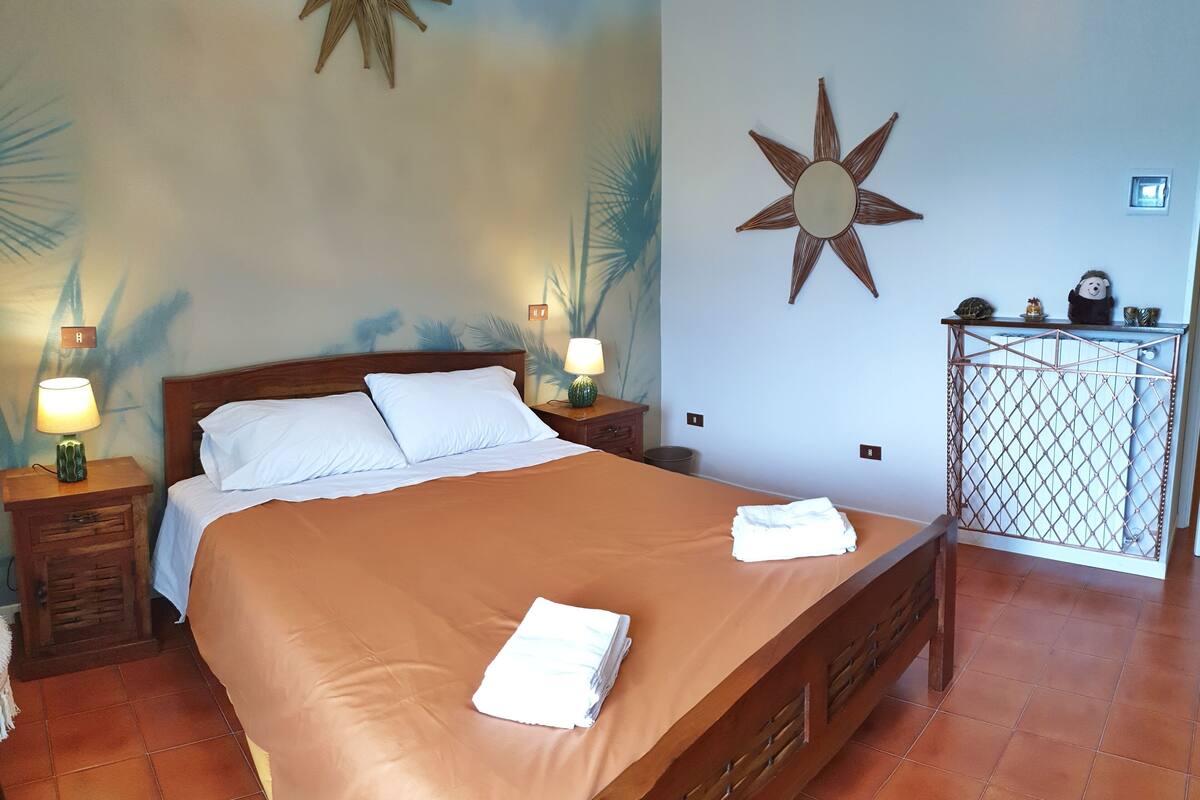 A neatly made bed with white linens, a wooden headboard, and a star-shaped wall decoration.