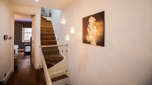 Un escalier avec des marches en bois et une rampe en métal, menant à une pièce comprenant un lit et une fenêtre.