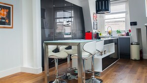 Une cuisine moderne dotée d’un îlot central, de tabourets de bar et d’un luminaire suspendu.