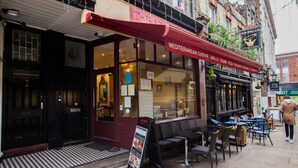 Un restaurant de cuisine méditerranéenne avec une terrasse et un sol à carreaux noirs et blancs.