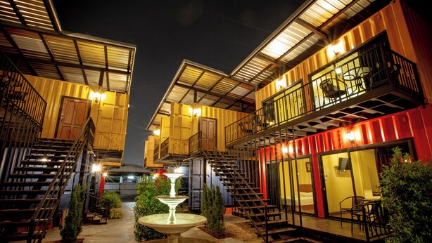 A hotel with multiple levels, outdoor seating, and a central fountain.