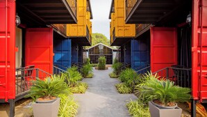 A pathway flanked by vibrant shipping containers leading to a building with a glass facade.