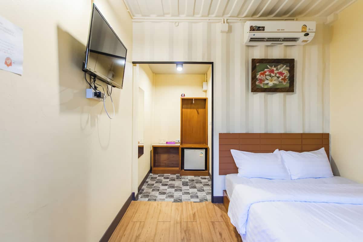 Une chambre d’hôtel équipée d’un lit, d’un téléviseur fixé au mur, d’un petit réfrigérateur et d’un appareil de climatisation.
