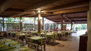 Ein Restaurant mit mehreren Tischen und Stühlen, überdacht mit einem Holzdach und Blick ins Freie.