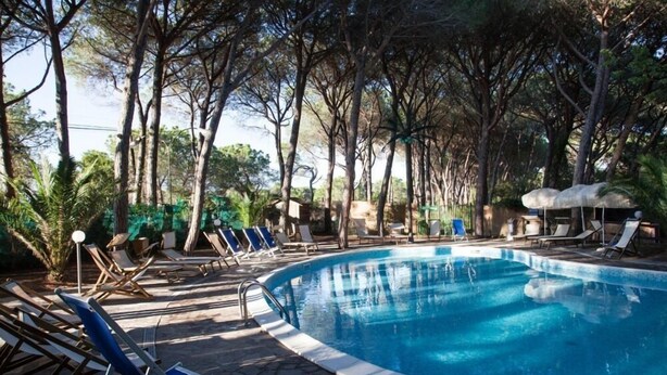 Zona de piscina con sillas de descanso y sombrillas.