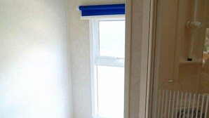 Un baño pequeño y limpio con inodoro, ventana y zona de ducha.