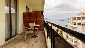 A balcony with a table and chairs, a view of the sea, and a distant island. - Regina City Hotel (Vlorë)