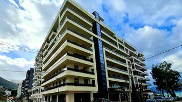 Un hotel de varios pisos con balcones, zona de estacionamiento y vistas al mar.
