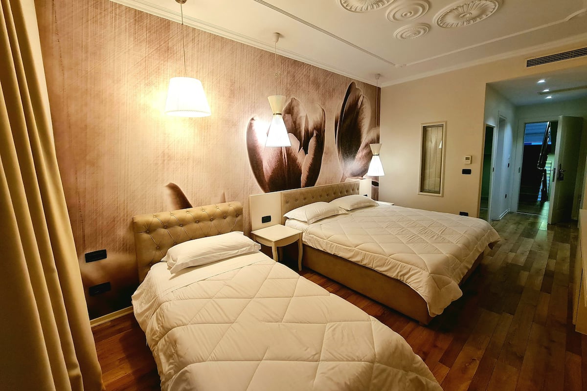 Une chambre d’hôtel avec deux lits, une grande fresque murale et un plancher en bois.