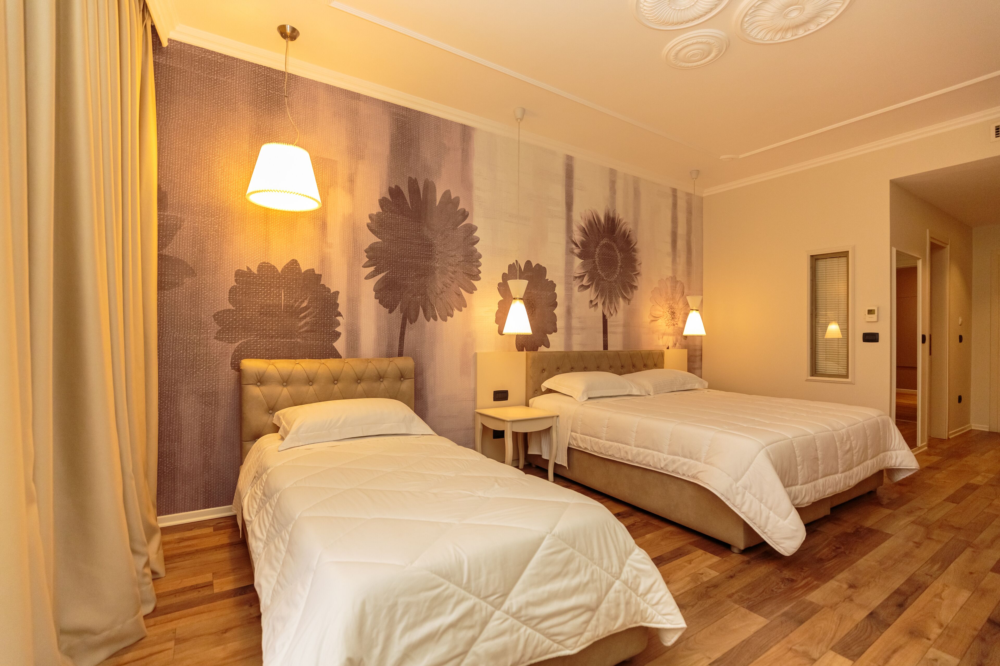 Een hotelkamer met twee bedden, een tafeltje en decoratieve wandkunst.