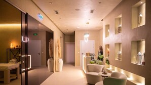 A modern hotel lobby with a reception desk, seating area, and decorative wall sconces. - Regina City Hotel (Vlorë)