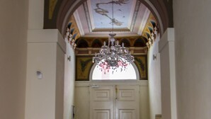 Un couloir agrémenté d’un lustre, de portes à double battant et d’un plafond orné de motifs.