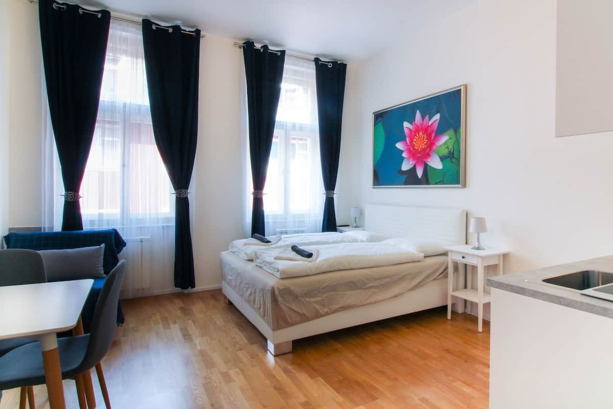 Una habitación de hotel con una cama, un escritorio, una silla, una mesita y un cuadro de una flor en la pared.