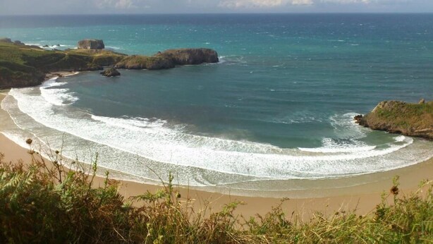 A coastal landscape with a sandy beach, rocky outcrops, and clear blue waters. - Hotel Rural Porrua (Llanes)