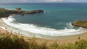 A coastal landscape with a sandy beach, rocky outcrops, and clear blue waters. - Hotel Rural Porrua (Llanes)
