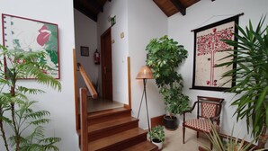 A staircase leading to a second floor, surrounded by potted plants and a chair with a patterned cushion. - Hotel Rural Porrua (Llanes)