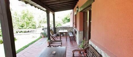 An outdoor patio with wooden furniture and potted plants.
