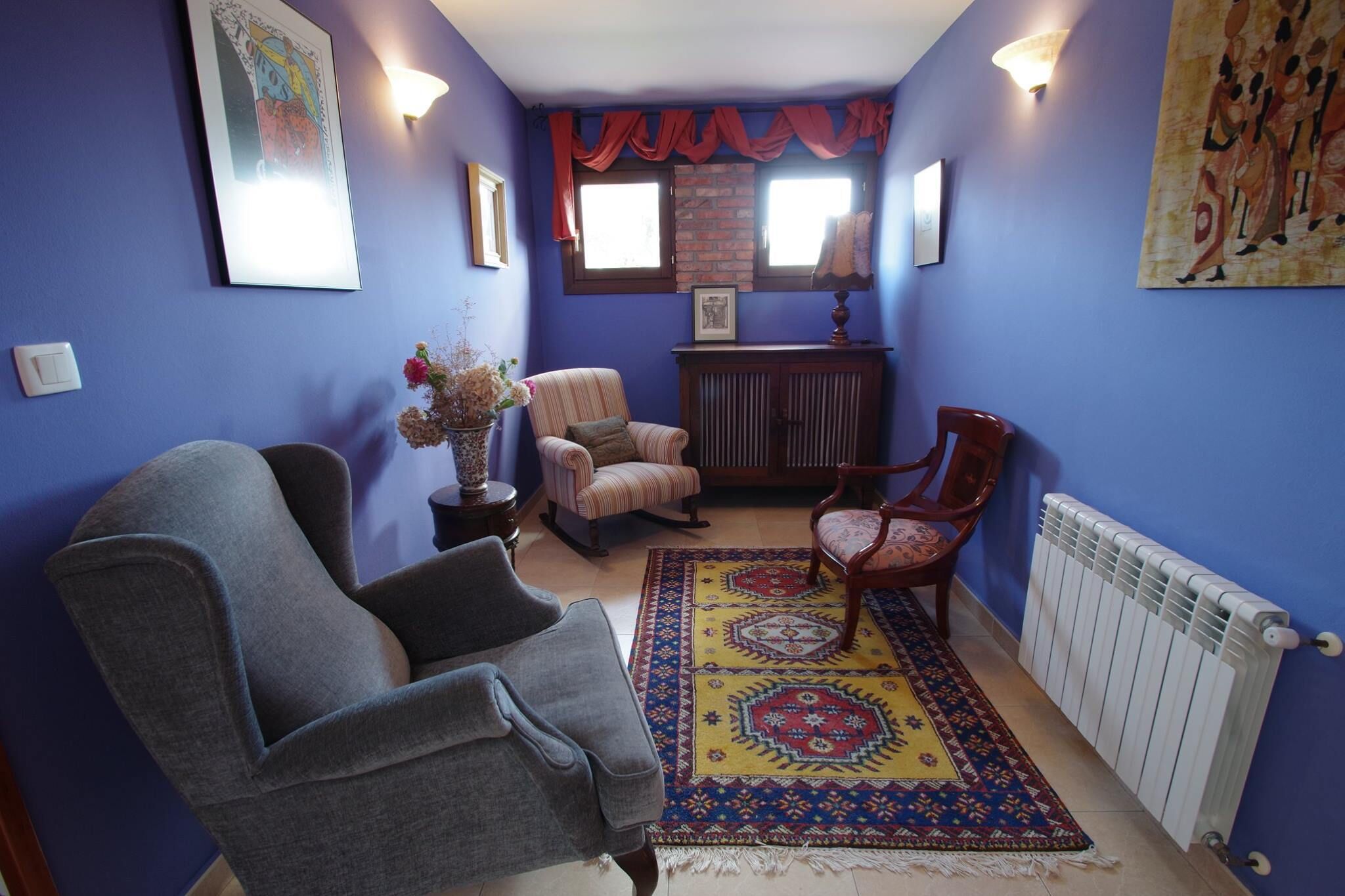 Un salon aux murs bleus, avec un tapis à motifs et deux fauteuils.