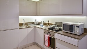 A modern kitchen with white cabinets, stainless steel appliances, and a microwave on the counter. - Silbury MK City Apartment With Parking (Milton Keynes)