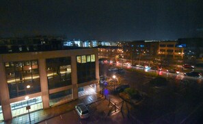 A nighttime view of a building with multiple windows and a parking area. - Silbury MK City Apartment With Parking (Milton Keynes)