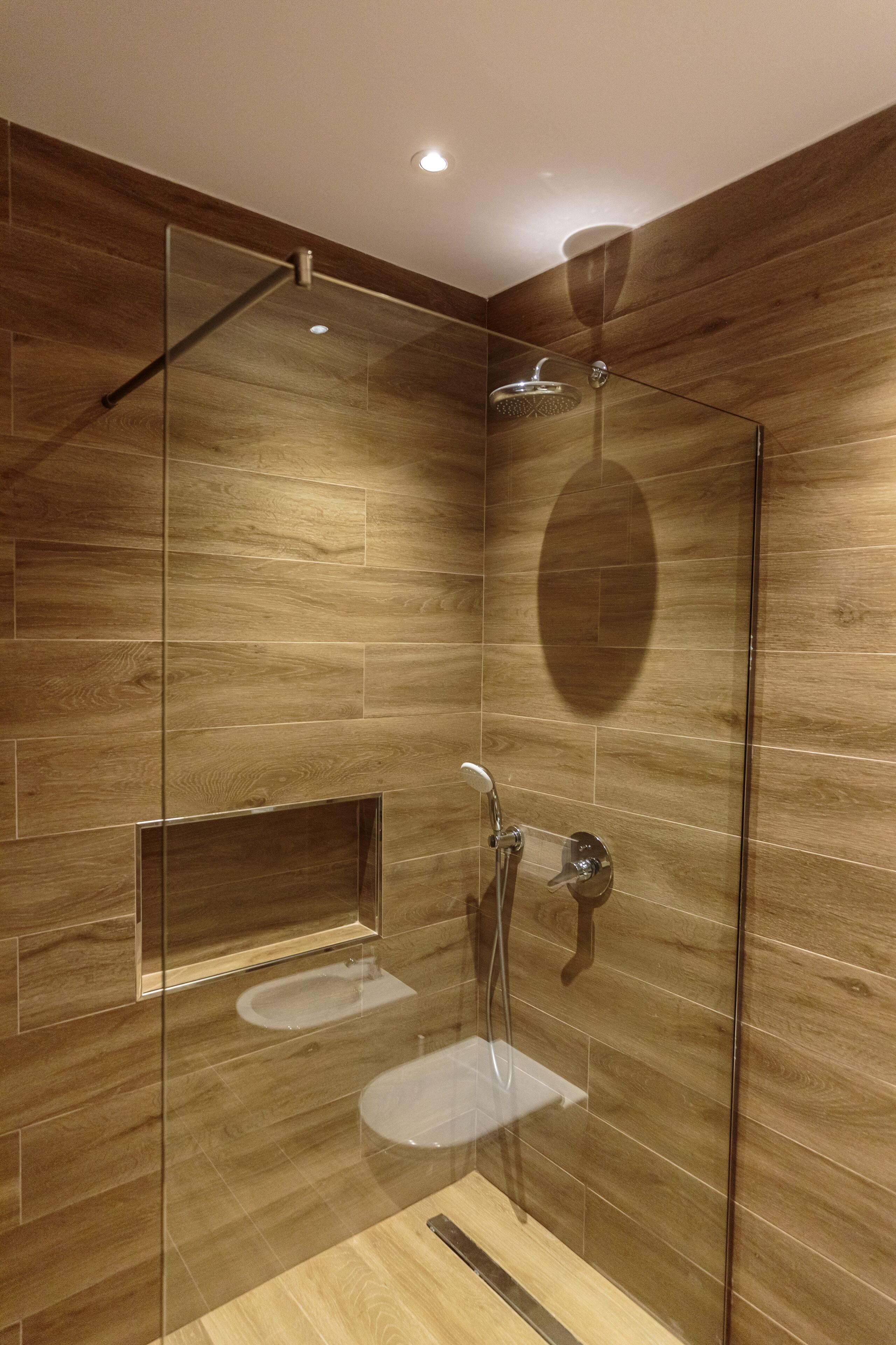 A modern bathroom with wooden paneling, a glass-enclosed shower, and a built-in sink.