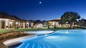 Piscina com estrutura de pedra e espreguiçadeiras.