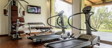 A gym with treadmills, weight machines, and dumbbells.