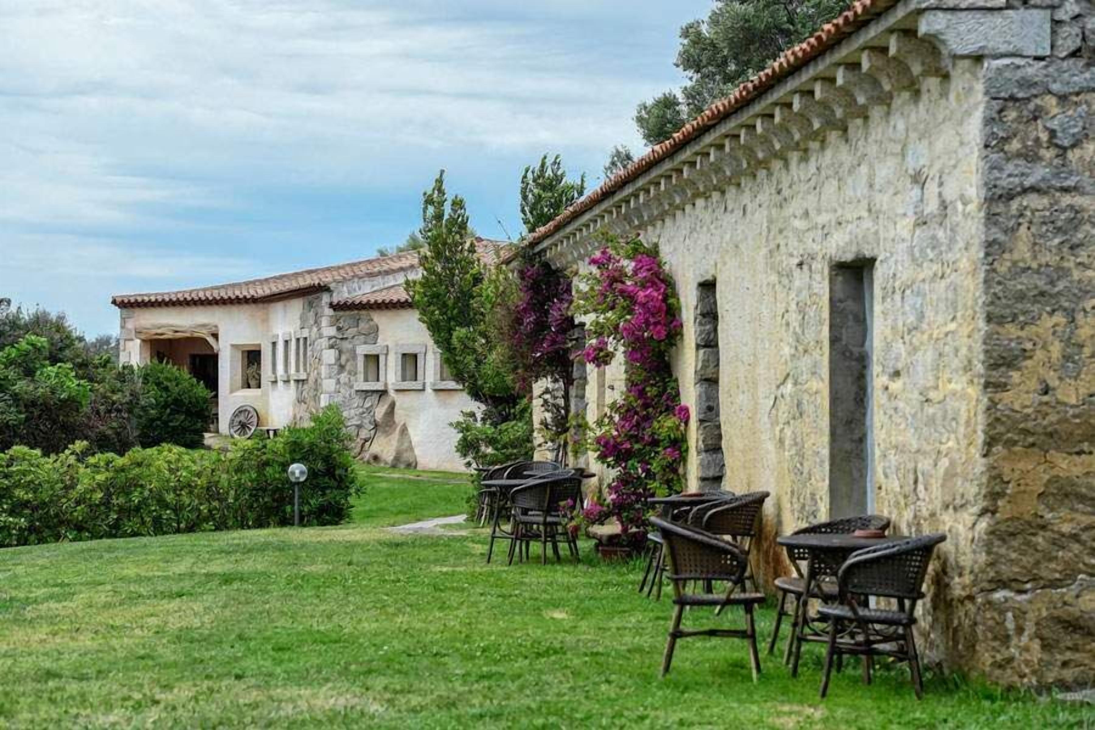 Un edificio de piedra con terraza y jardín.
