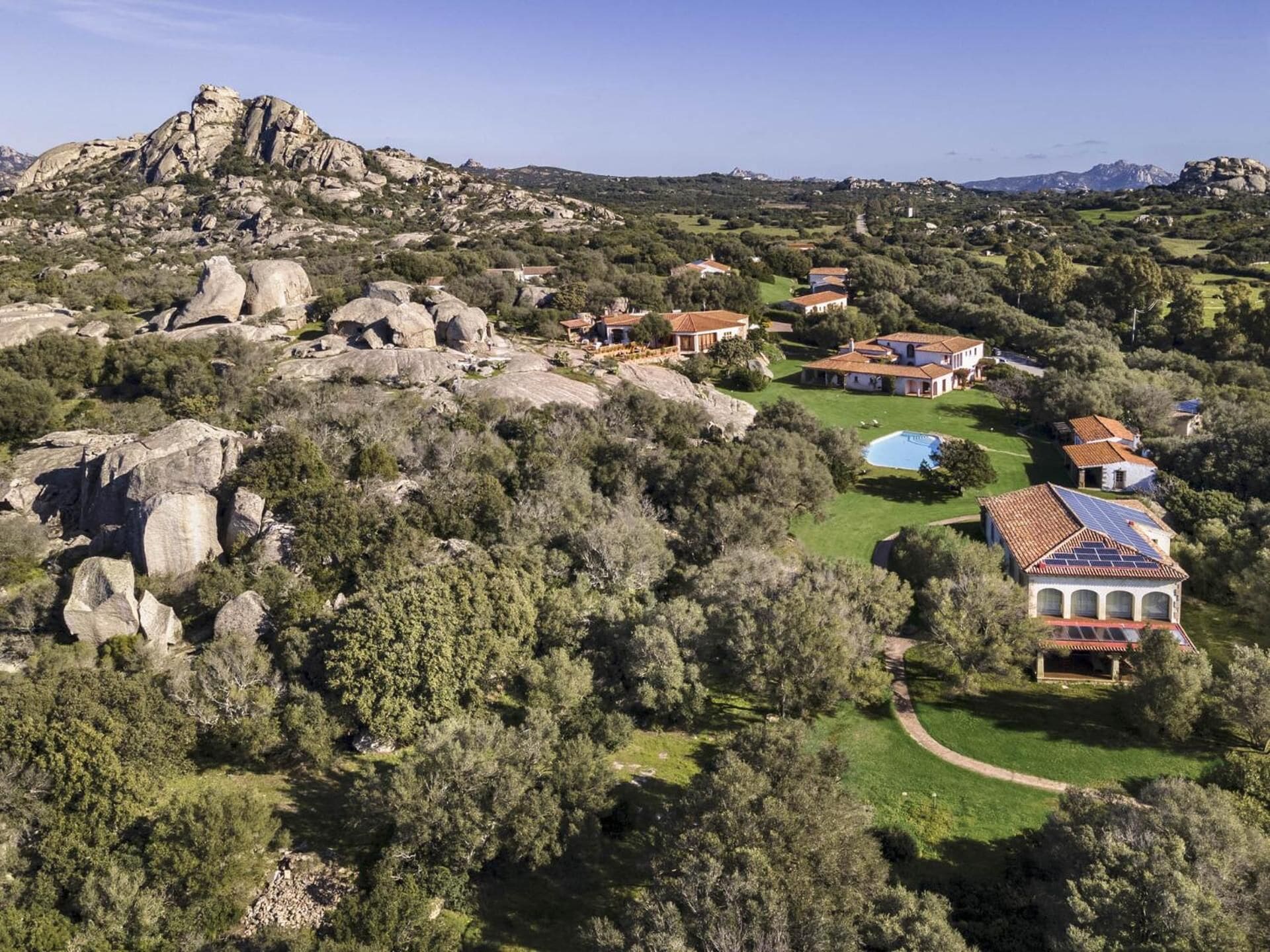 A residential area with houses surrounded by trees and rocky terrain.