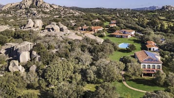 A residential area with houses surrounded by trees and rocky terrain.